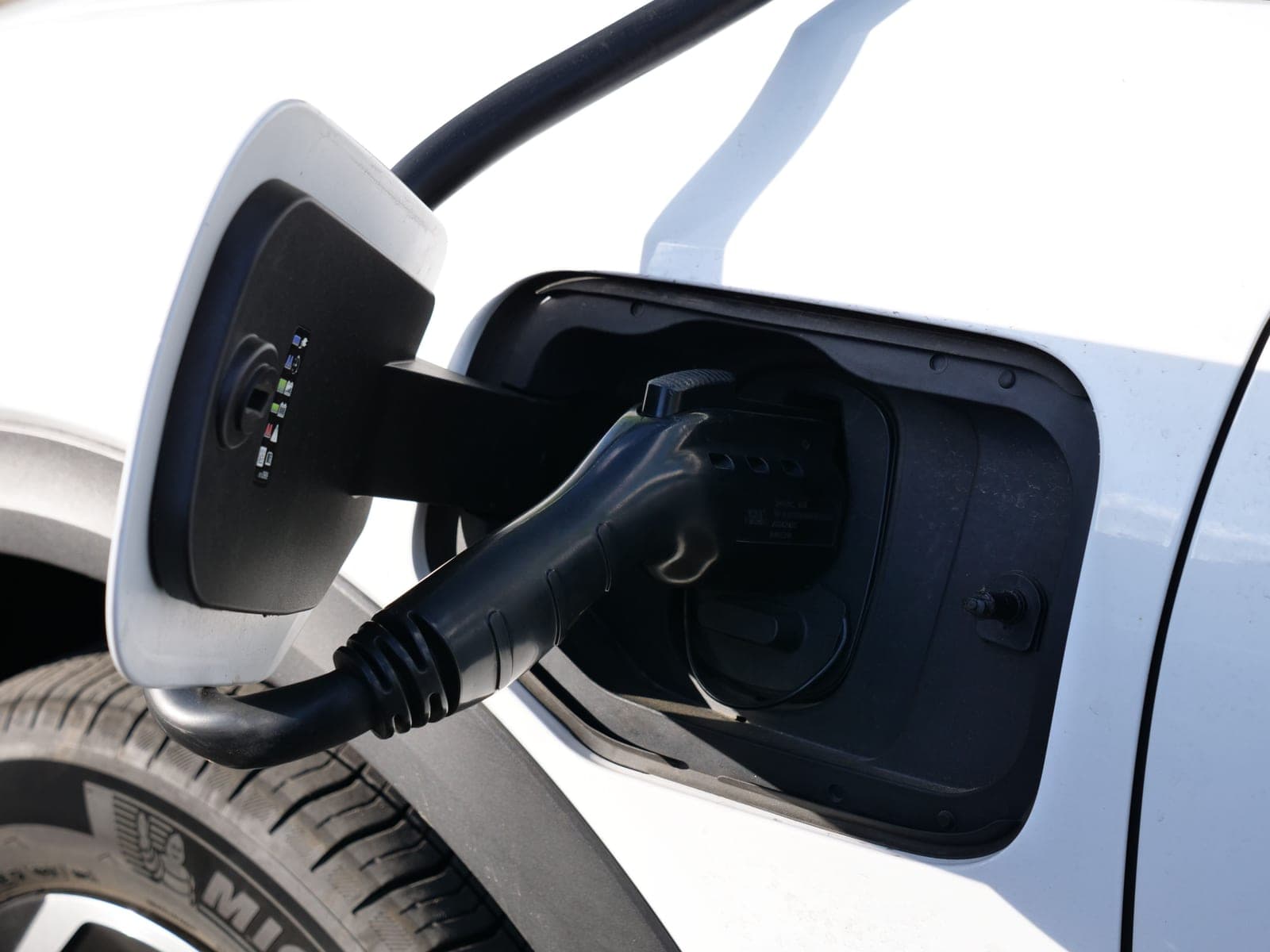 An electric vehicle charging connector plugged into a car's charge port